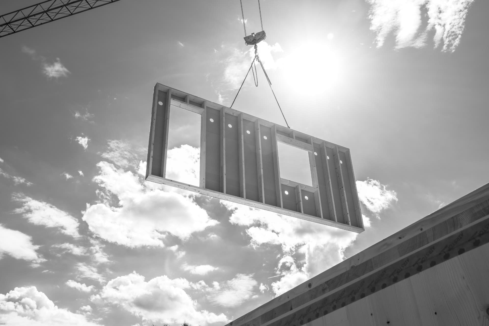 Baukran hebt eine vorgefertigte Holzwand vor der Sonne