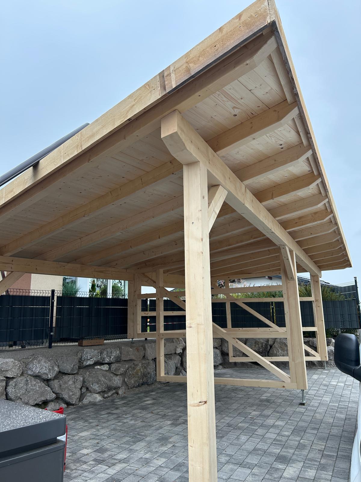 Carport aus massiven Holzbalken mit offener Dachkonstruktion