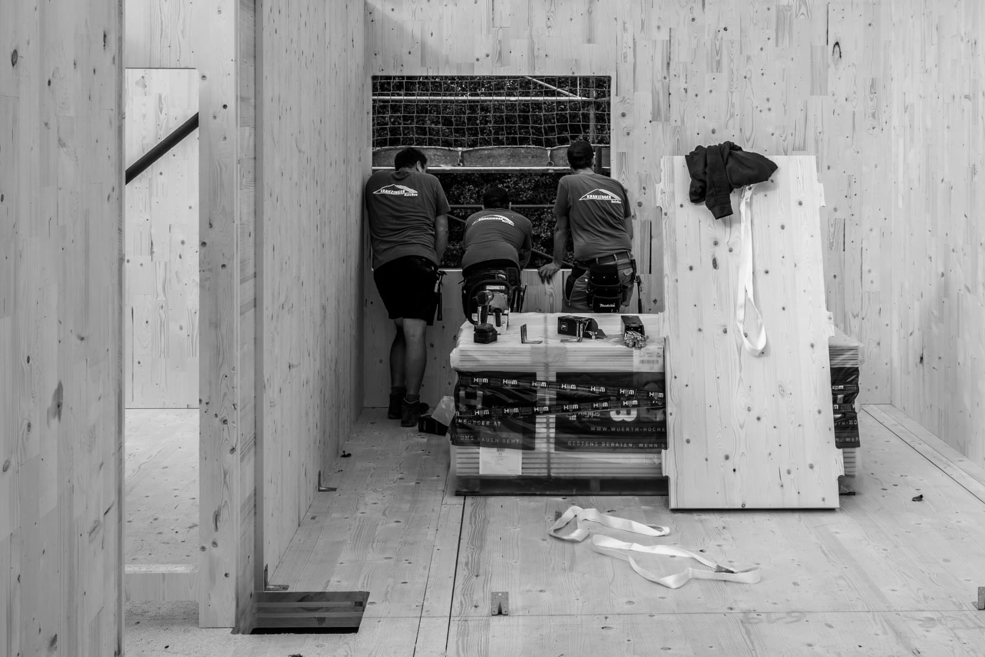 Drei Mitarbeiter von Kranzinger Holzbau beim Einbau von Massivholzelementen auf der Baustelle